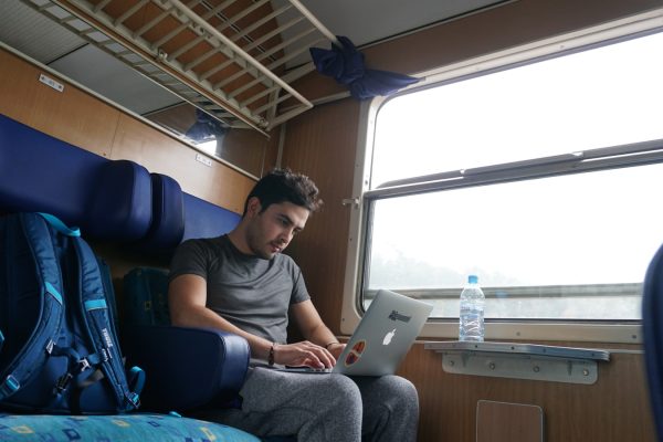 a man sitting on a train looking at his laptop